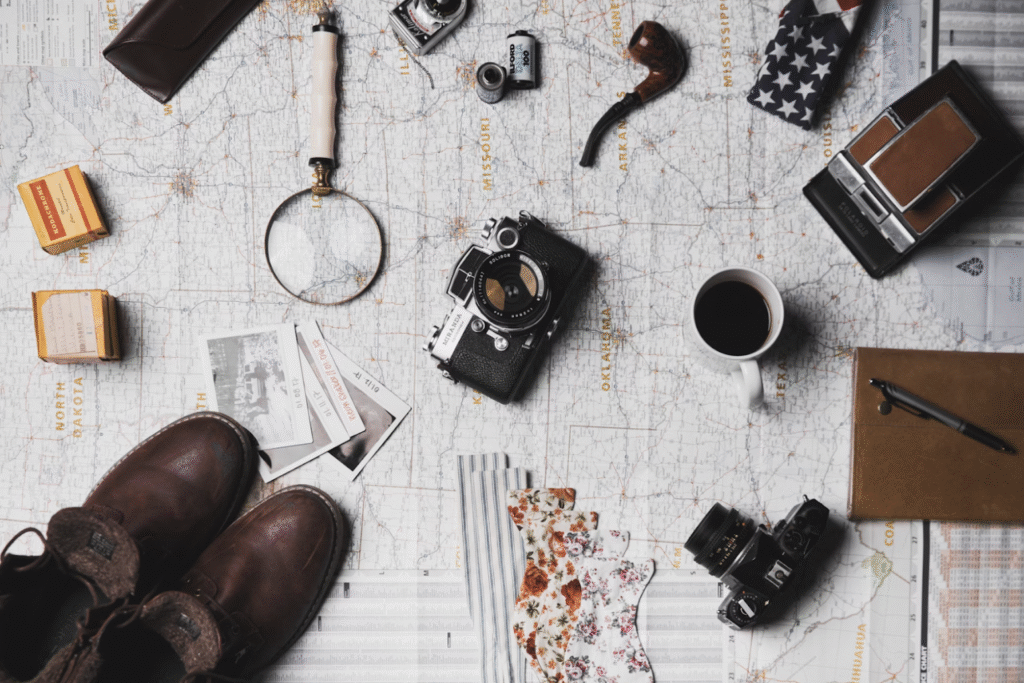 camera-hiking-boots-pipe-mug-magnifying-glass-and-tickets-on-map